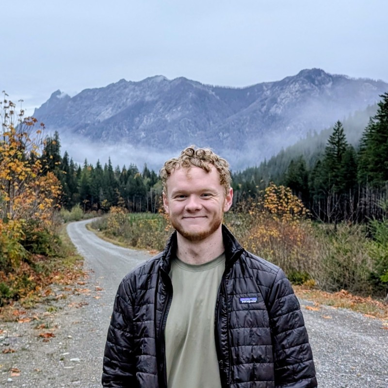 Dylan, standing on a gravel road in front of misty mountains